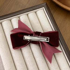 Elegant wine red velvet bow hair clip with silver metal alligator clamp on a display tray