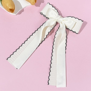 Detail of elegant cream double bow hair clip with lace ribbon and black wave embroidery