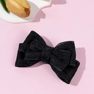 Detailed close-up of a layered black lace bow hair clip with intricate crochet floral patterns