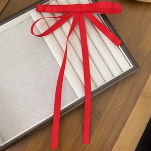 Primo piano di un grande fiocco in raso rosso con lunghi nastri su un vassoio beige