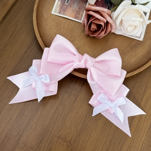Lolita pink ribbon hair clip with layered satin bows and white accents in a wooden tray