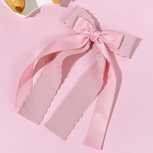 Detail of pink double-layer bow hair clip with glossy ribbon and lace texture