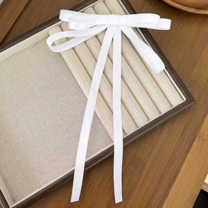 Dettaglio di un elegante fermaglio per capelli a fiocco bianco con nastri lunghi