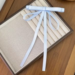 Elegante fermaglio per capelli con fiocco in raso celeste su tavolo in legno per donna