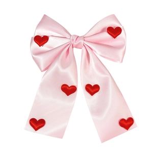 Elegant pink satin bow hair clip with red heart accents and long streamers on white background