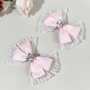 Close-up of pink satin bow hair clips with white lace edges and rhinestone butterfly