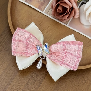 Détail de barrette à nœud en tweed rose et satin blanc avec papillon strass et perle