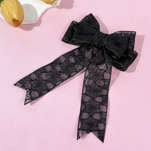 Close-up of elegant black lace bow hair clip with floral patterns and long ribbons