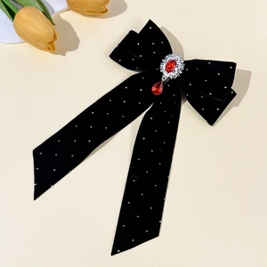 Detail of black velvet bow hair clip featuring a ruby pendant and small white pearls