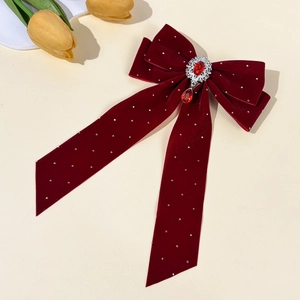 Detailed macro view of velvet bow hairclip featuring a ruby red gemstone pendant
