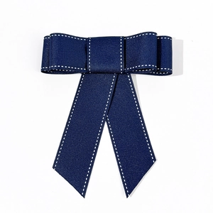 Detail van donkerblauwe stoffen haarstrik met witte stiksels en lange hangende linten