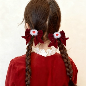 Dettaglio di fermagli per capelli a fiocco rosso velluto con pompon bianchi su trecce