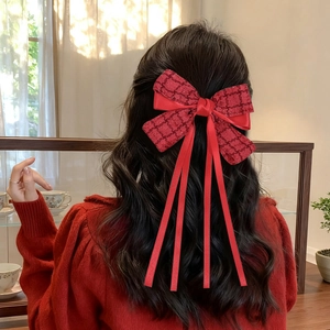 Detail view of a large red bow hair clip with long ribbons on a half-up hairstyle