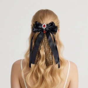 Close-up of black lace bow hair clip with ruby pendant and elegant long satin streamers