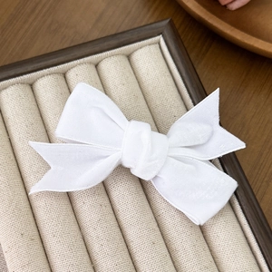 Macro detail of high-quality white velvet bow hair clip showing elegant fabric texture