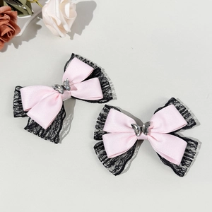 Detail of pink satin bow hair clips with black lace edges and silver crystal butterfly