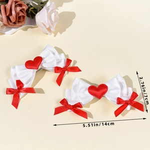 Detail view of large white satin bow hair clips with red hearts and ribbon accents