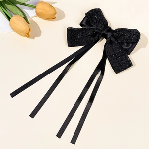 Detail of elegant black lace bow hair clip with flowing long satin ribbons and pearls