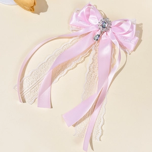 Detailed view of pink ribbon bow hairpin with lace trim and dangling teardrop gemstone