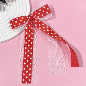 Barrette à cheveux nœud rouge à cœurs avec dentelle blanche sur fond rose doux