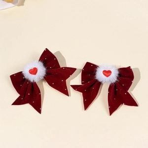 Dettaglio di fermagli in velluto bordeaux con strass lucidi e pompon di peluche bianco