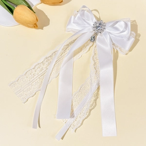 Detailed macro view of white lace satin bow hair clip with crystal pendant and rhinestones