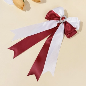 Macro detail of red and ivory bow hair clip with oval gemstone and teardrop pendant