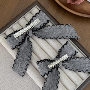 Elegant grey fabric bow hair clips with black wave stitching and silver alligator grips