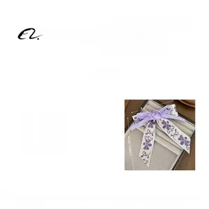 Detail of purple fabric hair clip showing floral embroidery texture and dimensions
