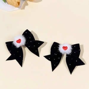 Dettaglio di fiocchi per capelli in velluto nero con pon pon bianchi e strass a cuore rosso