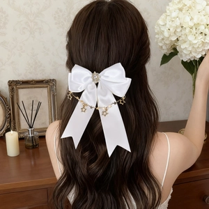 Detail einer weißen Satinschleife Haarspange mit goldener Sternenkette und Perlen
