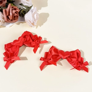 Pair of sweet red satin bow hair clips with central heart elements for a romantic style