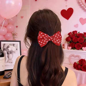 Détail d'un nœud papillon rouge à motifs de cœurs porté sur de longs cheveux bruns