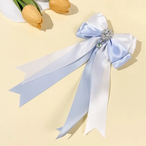 Detailed view of blue and white satin bow hair clip with rhinestone and emerald pendant