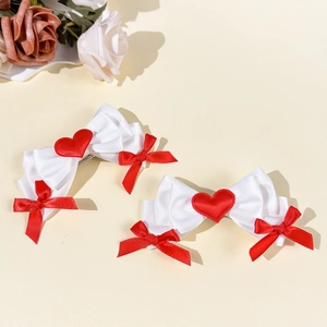 Detailed close-up of layered white satin bows with red heart and silk ribbons for hair
