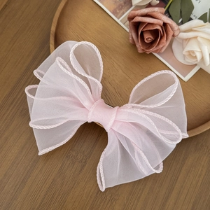 Dettaglio di un fermaglio per capelli in organza rosa chiaro con bordi ondulati