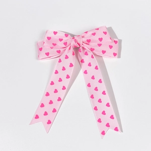 Détail d'une barrette à cheveux nœud rose avec texture côtelée et motifs cœurs