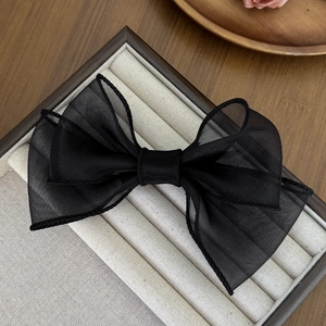 Vue détaillée d'une grande pince à cheveux en organza noir sur un plateau en bois chic