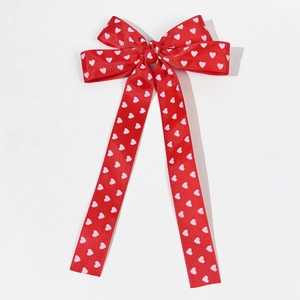 Détail d'un nœud en ruban gros-grain rouge avec motif de cœurs et longues banderoles