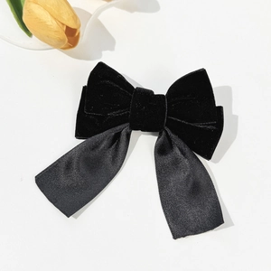 Elegant vintage black velvet and satin ribbon bow hair clip on a clean cream background
