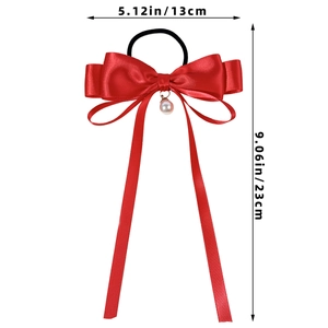 Detailed view of a red ribbon bow hair tie with pearl pendant and 23cm ribbon length