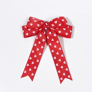 Détail d'un nœud en ruban gros-grain rouge avec motifs de cœurs et longs rubans
