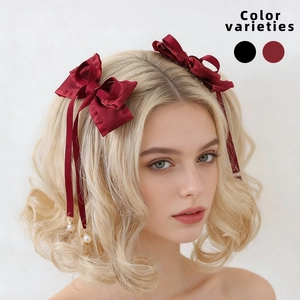 Detail of red satin bow hair clip with ribbons and pearls on blonde ponytail