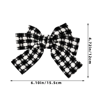 Detail of houndstooth bow hair clip showing tweed texture and 15.5cm width dimensions