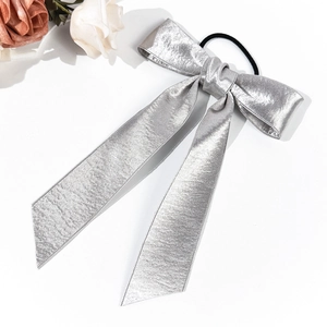 Détail d'un chouchou en satin argenté avec nœud et rubans longs à texture métallique