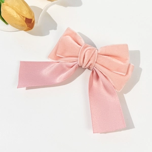 Detail of pink velvet and satin bow hair clip with elegant layered texture on white background