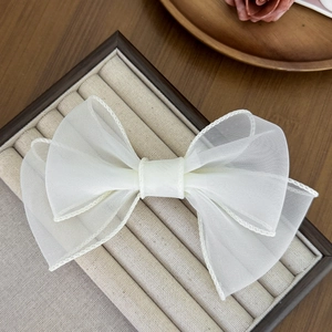 Détail de la pince à cheveux en organza blanc montrant la texture fine et le nœud 3D