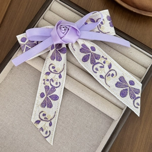 Macro detail of Chinese style purple satin bow hair clip with handmade 3D fabric rose flower