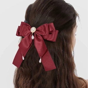 Detail einer burgunderroten Satinschleife Haarspange mit elegantem Perlenanhänger