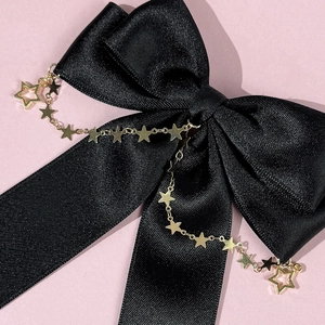 Elegant black satin bow hair clip featuring a gold star chain tassel on a purple background